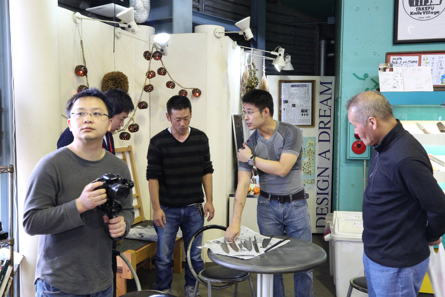 Craftsmen gathered around knives on a round table at Takefu Knife Village, October 2015