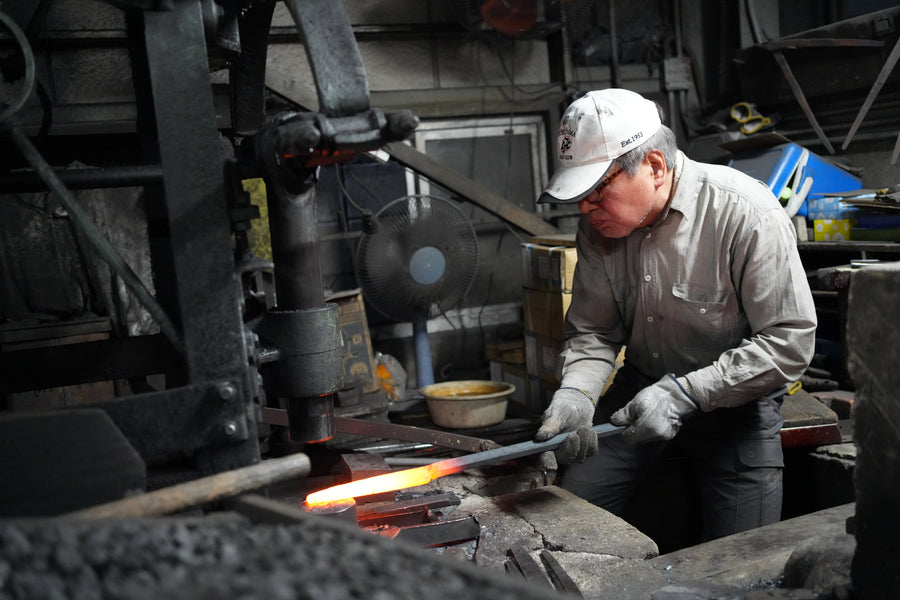 Itsuo Doi draws heated steel from the forge at the power hammer, December 2023.