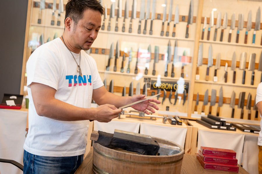 Shibata-san inspecting a blade beside the sharpening barrel at Knives & Stones, Sydney