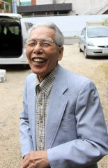 Keijiro Doi outdoors in later life, laughing by a van, photographed by Suisin